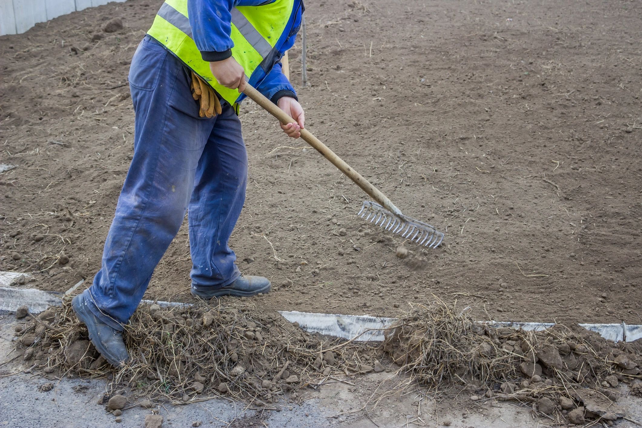Crew member raking and preparing soil for a new lawn